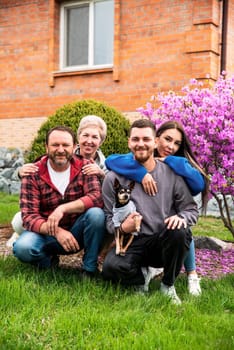 Portrait of happy family together hugging near their big house.