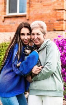 portrait of daughter-in-law hugs mother-in-law and holding dog