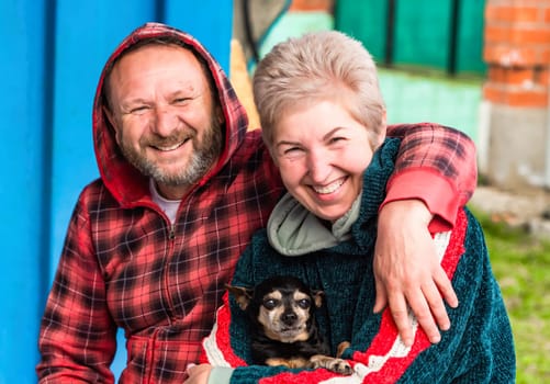 Mature russian married couple hugging and holding a dog