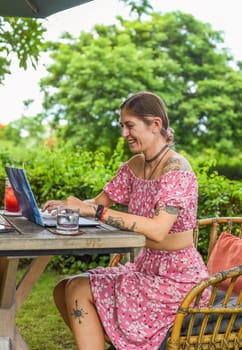 Cute videographer and vlogger taking a video with laptop camera  in summer garden