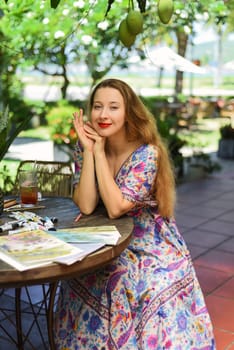 Portrait of beautiful blonde woman artist and illustrator  sitting by the table with drawings, brushes and paint