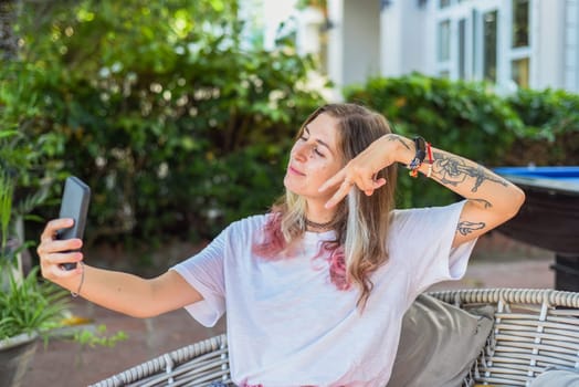 Cute woman taking a photo selfie and waving to a camera in the evening