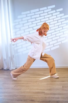 A dancer showcases an expressive pose in a well-lit studio adorned with soft shadows. The artist wears casual clothing and focuses on movement, embodying creativity and fluidity.