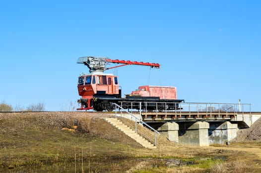 Red railroad crane on the bridge in 
countryside