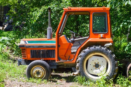 Old orange tractor with no doors, with a pipe. Russian countryside