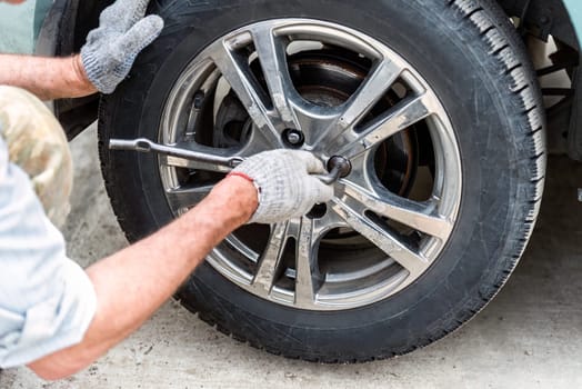 young man changing a car tire for winter tires