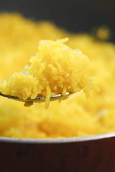 A close-up of golden saffron rice being stirred in a pot.
