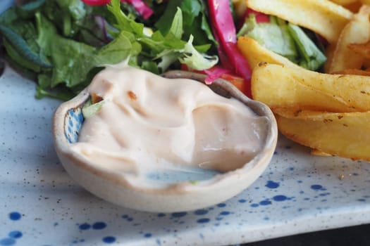 A creamy dipping sauce accompanies a vibrant salad and crispy fries.