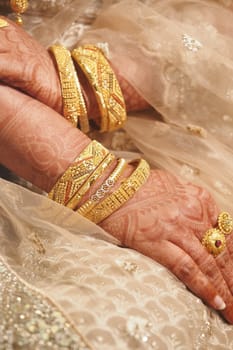 Hands showcasing intricate henna designs and multiple golden bangles.