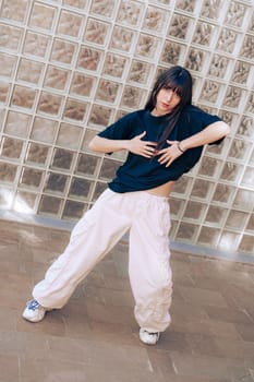 A dancer showcases dynamic choreography in an outdoor urban area, blending creativity and passion under bright sunlight while wearing comfortable street attire.