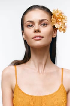 Confident young model in an orange outfit, adorned with a flower, showcasing a warm expression. Ideal for summer or spring fashion themes and lifestyle photography.