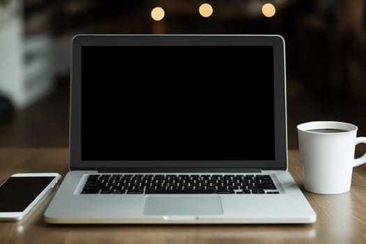 A modern workspace featuring a laptop, smartphone, and coffee mug on a wooden table with soft natural lighting. Ideal for remote work and productivity themes.
