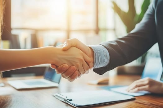 Two business professionals share a confident handshake in a bright office setting, symbolizing agreement and collaboration. The modern workspace enhances the moment.