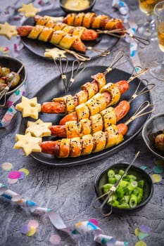 Carnival food, long sausages wrapped in yeast dough, corn dog with mustard and olives 