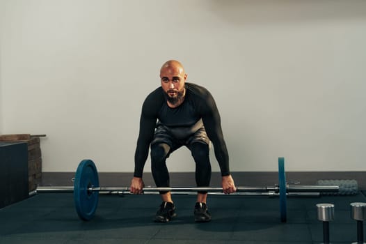 A person is preparing to lift a barbell in a modern gym setting. The individual is focused on the exercise, showcasing strength and determination during the fitness session.