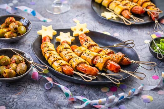 Carnival food, long sausages wrapped in yeast dough, corn dog with mustard and olives 