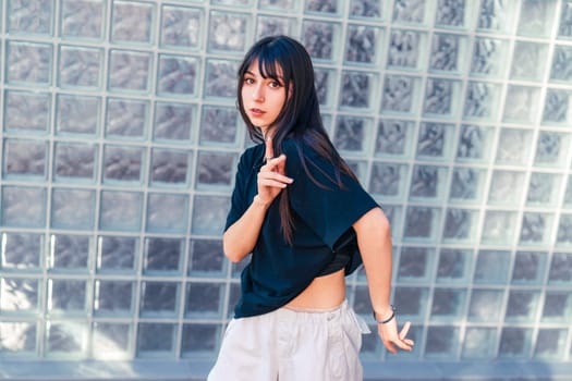 In a bright urban space, a young woman showcases her dance skills with graceful movements. She wears casual attire and expresses creativity through her art.