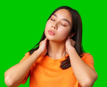A young woman appears to be in a moment of relaxation, with her eyes closed and hands gently holding her neck.