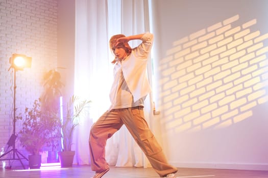 A dancer showcases an expressive routine in a brightly lit studio, surrounded by indoor plants and vibrant lighting. The atmosphere is creative and dynamic, reflecting artistic energy.