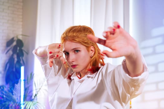 A dancer exhibits impressive skills with delicate hand gestures and a focused expression in a modern studio adorned with vibrant lighting. The creative atmosphere enhances the performance.