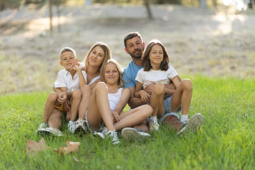 Family enjoying a relaxing day sitting on green grass in a sunny park