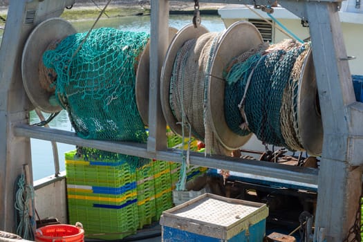 A fishing boat with a large green rope hanging from the top. The rope is attached to a large blue and green net