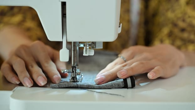 Close up of professional seamstress working on a sewing machine. Creative entrepreneurship concept.