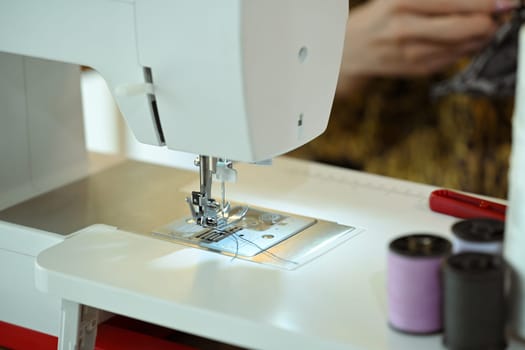Close up of a sewing machine with thread and fabric at fashion designer workspace.