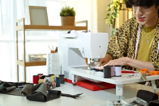 Young fashion creator crafting a unique clothing design in cozy studio.