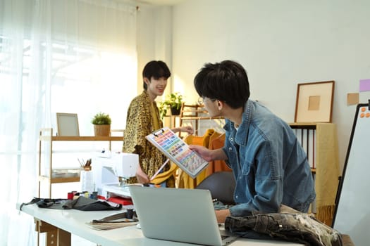 Fashion designers collaborating on a new clothing collection in a creative studio.