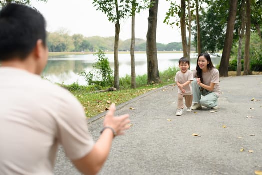 Excited little child running to father with open arms in the park.