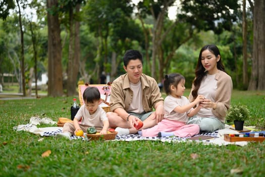 Cheerful asian family having fun together while doing picnic in the park.