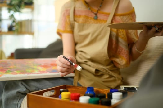 Close up of talented painter choosing paint for a canvas.