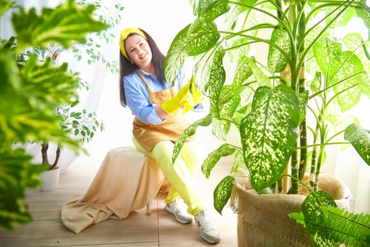 The gardener smiles while caring for thriving plants in a bright, cheerful greenhouse.