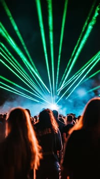People watching amazing laser show with green lights at night during live music concert