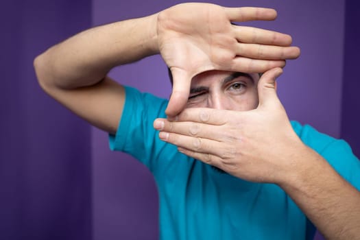 A man uses his hands to creatively frame a shot, showcasing a vibrant and playful artistic approach to photography