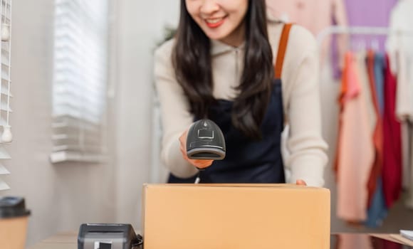 A diverse young woman using a barcode scanner to scan a cardboard box in a retail environment, preparing for inventory management.