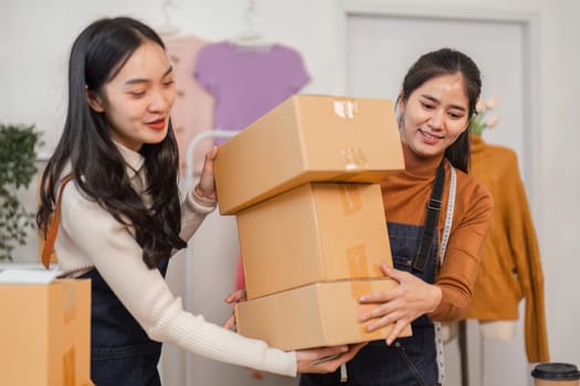 Two diverse female e-commerce employees stacking packages for delivery while organizing inventory in a retail store.