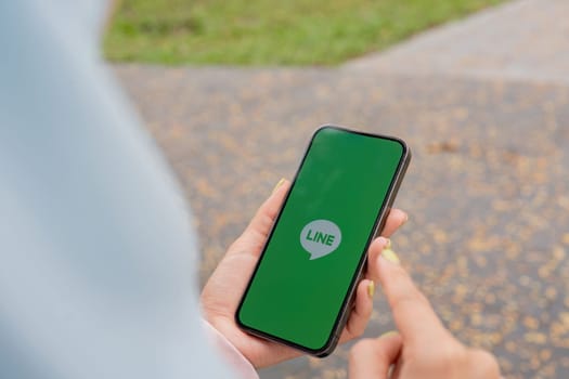 CHIANG MAI, THAILAND - January 27,2025 : Woman holding Apple iPhone with LINE apps on screen. LINE is a new communication app which allows you to make free voice calls and send free messages.