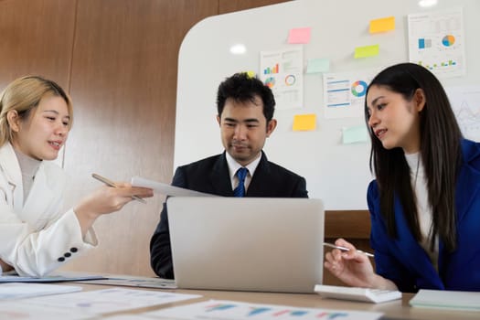 A diverse business team engaged in a strategy meeting, sharing reports and discussing analysis, highlighting effective communication and teamwork in a contemporary workspace.