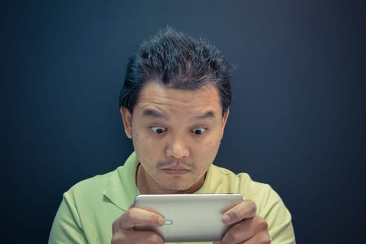 Asia man dazed and shock using smartphone on black background , process in vintage style