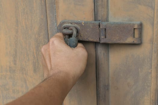 Locked vintage wooden door for safety with a hand of person