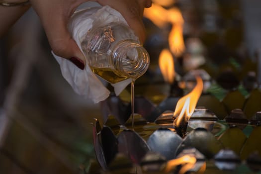 Filling the oil into Thai style metal candle lantern in Thai temple
