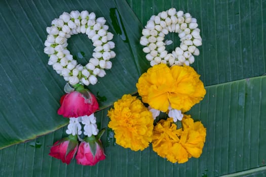 Beautiful garland jasmine and rose and calendula flower on green banana leaf