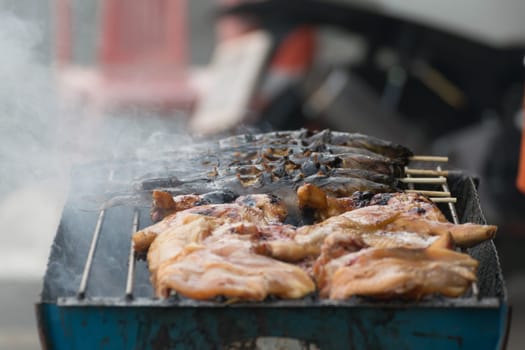 Thai street food with grilled fish and chicken in market.
