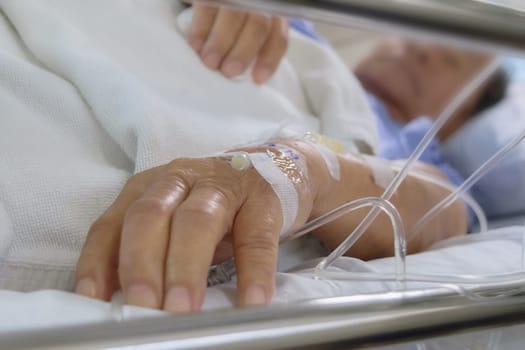 A patient in the hospital with saline intravenous, in Asian elderly man hand. Blurred his face