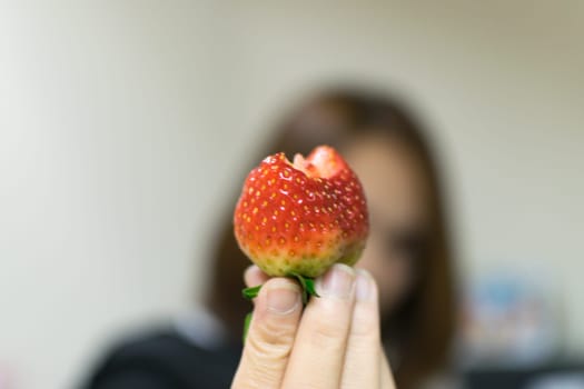 Strawberry holding on asian girl hand, defocus on girl background