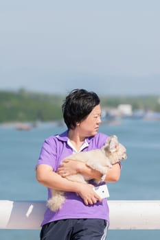 Asia woman plump body and her dog standing at estuary (river side and sea) when travel