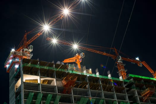 Nighttime and crane working with building construction in city