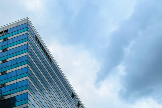 Big glass building with blue sky and storm cloud